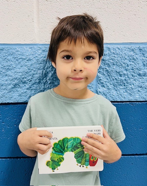 student receives praise award holding a book