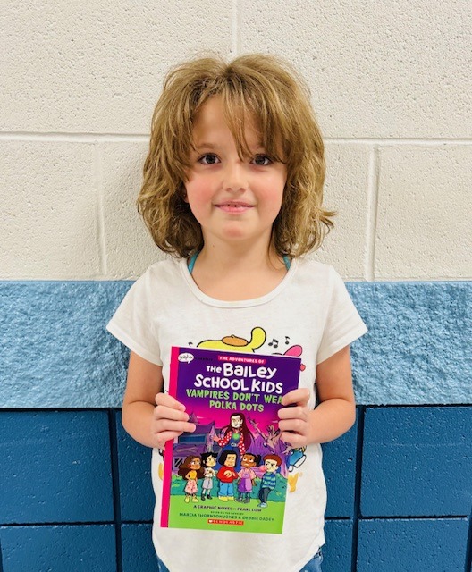 student receives praise award holding a book