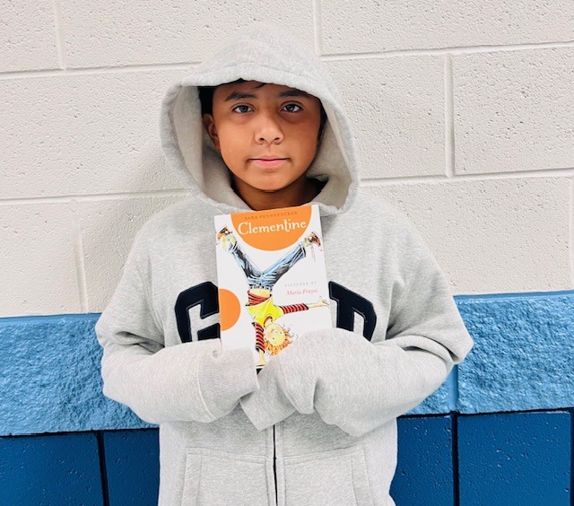 student receives praise award holding a book