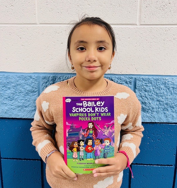 student receives praise award holding a book