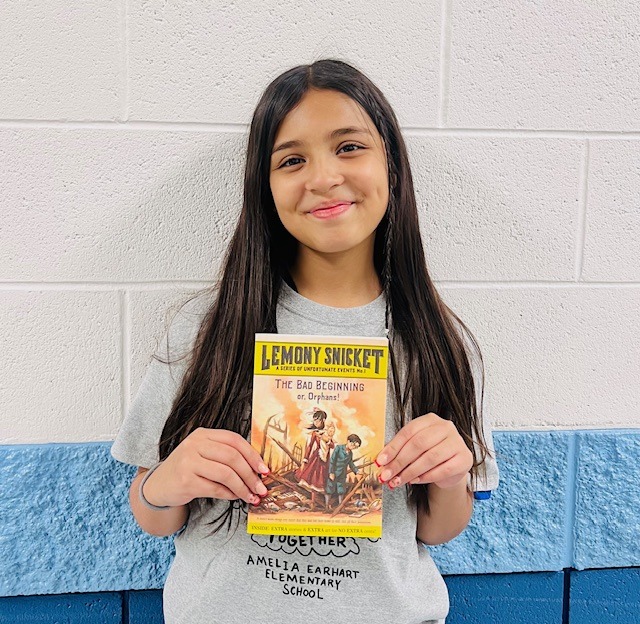 student receives praise award holding a book