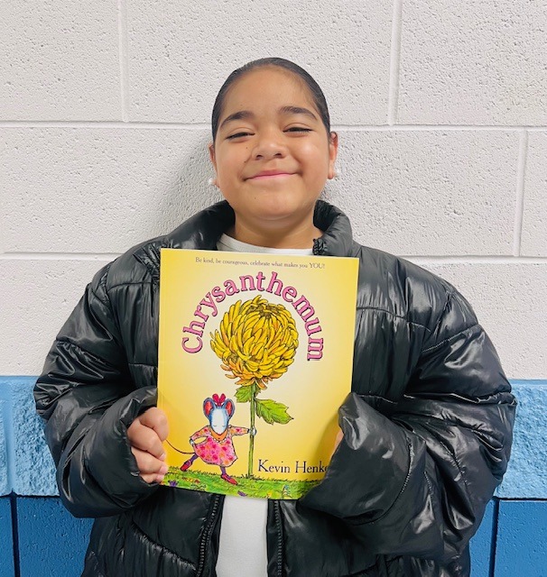 student receives praise award holding a book