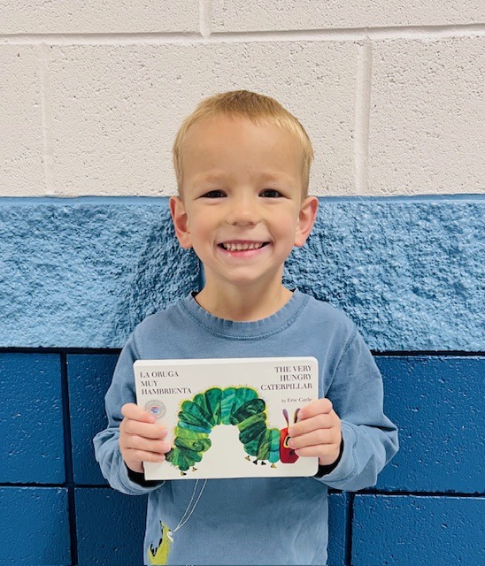 student receives praise award holding a book