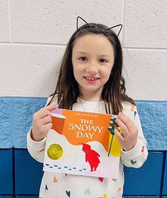 student receives praise award holding a book