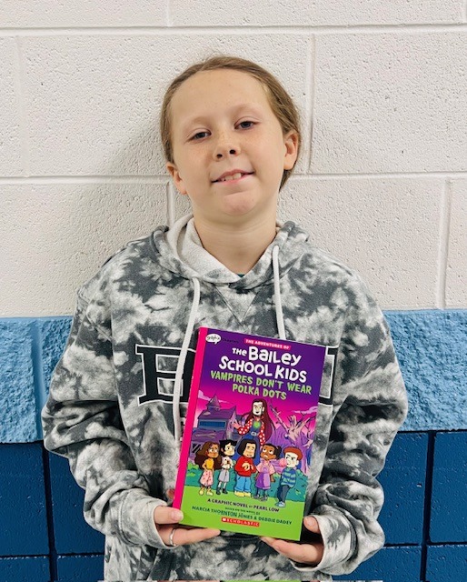 student receives praise award holding a book