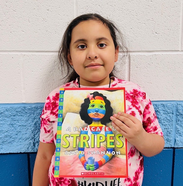 student receives praise award holding a book