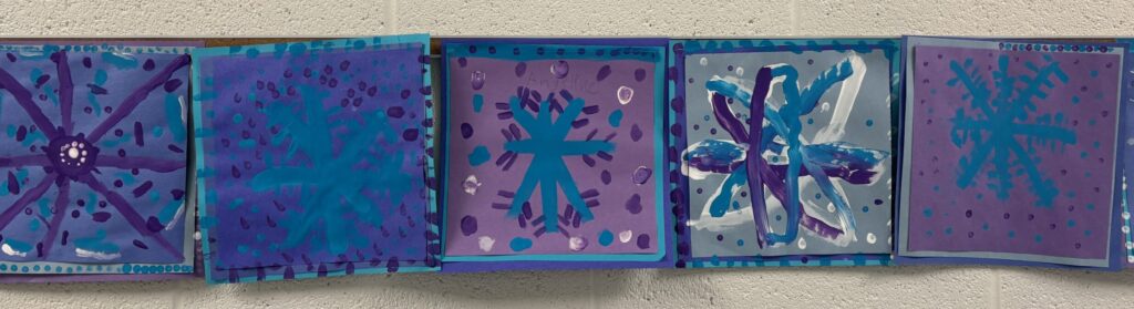 Symmetry art of snowflakes in blue, white and violet from the art classroom.