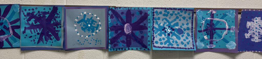 Symmetry art of snowflakes in blue, white and violet from the art classroom.