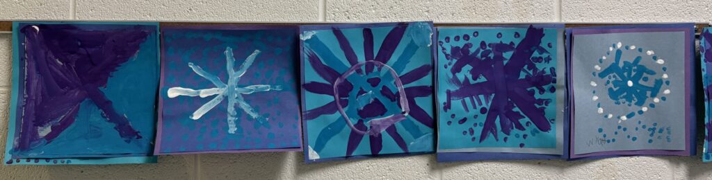 Symmetry art of snowflakes in blue, white and violet from the art classroom.