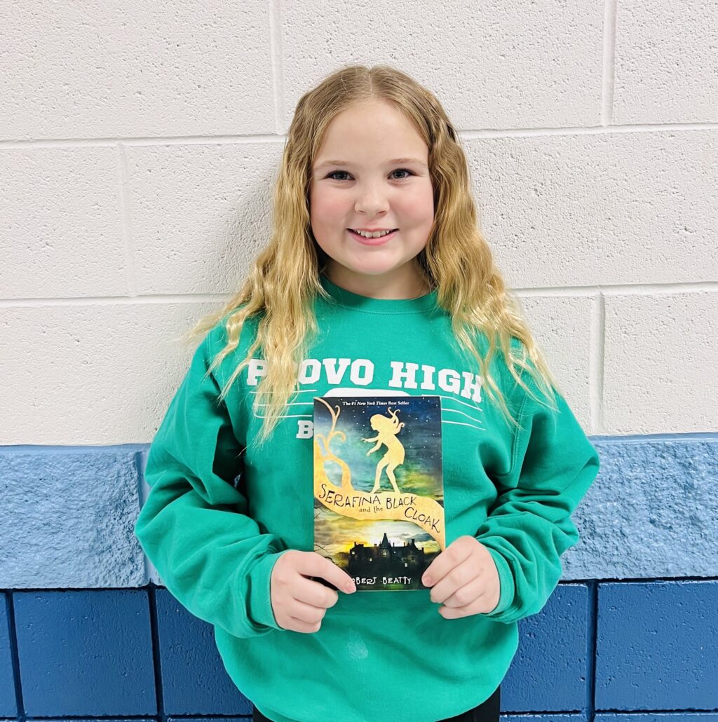 student holding a book they earned through a special recognition