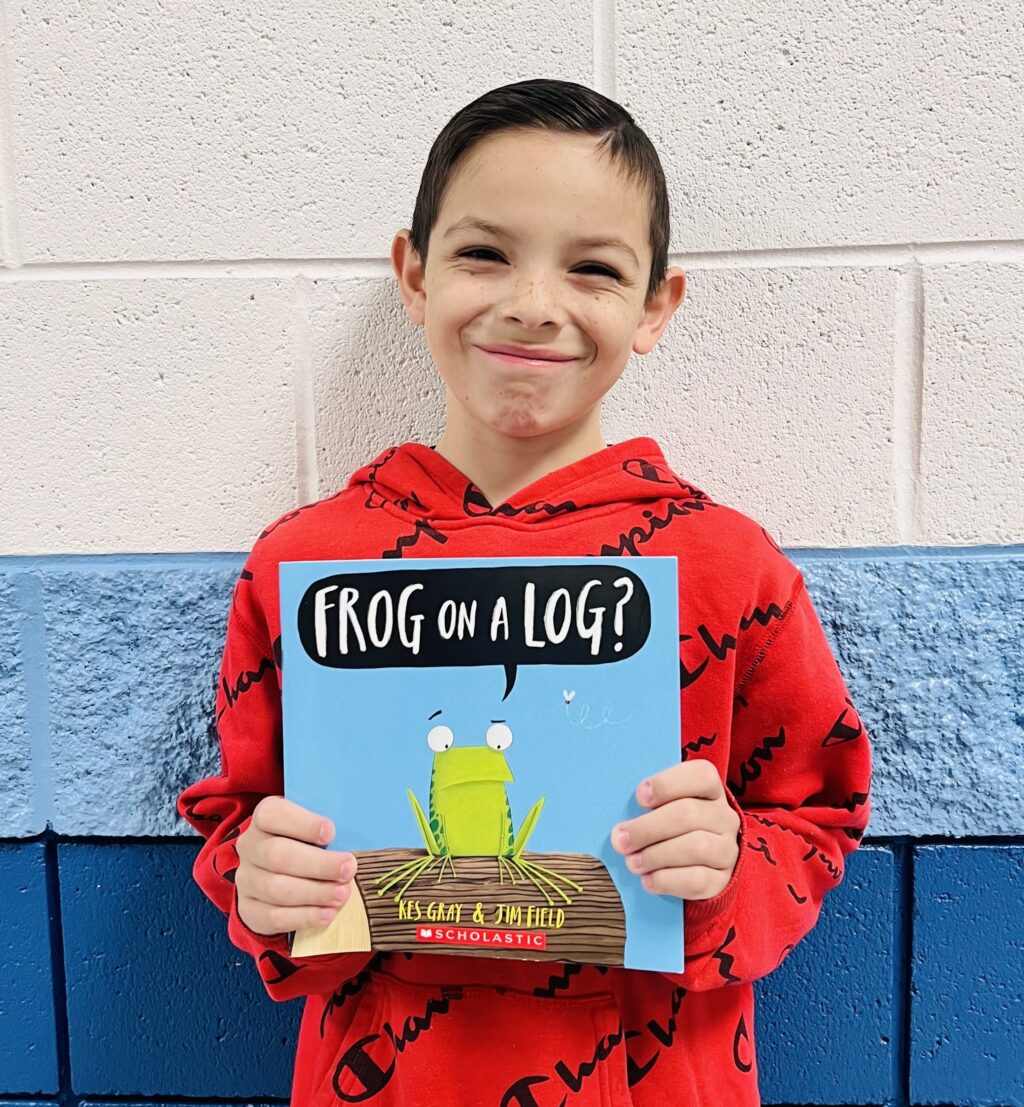 student holding a book they earned through a special recognition