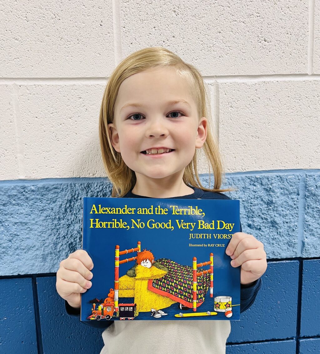 student holding a book they earned through a special recognition