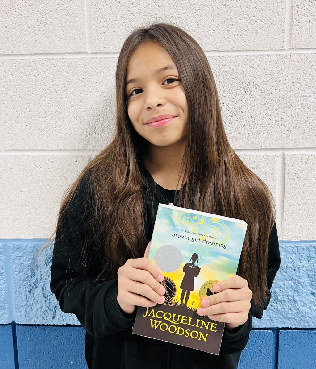 student holding a book they earned through a special recognition