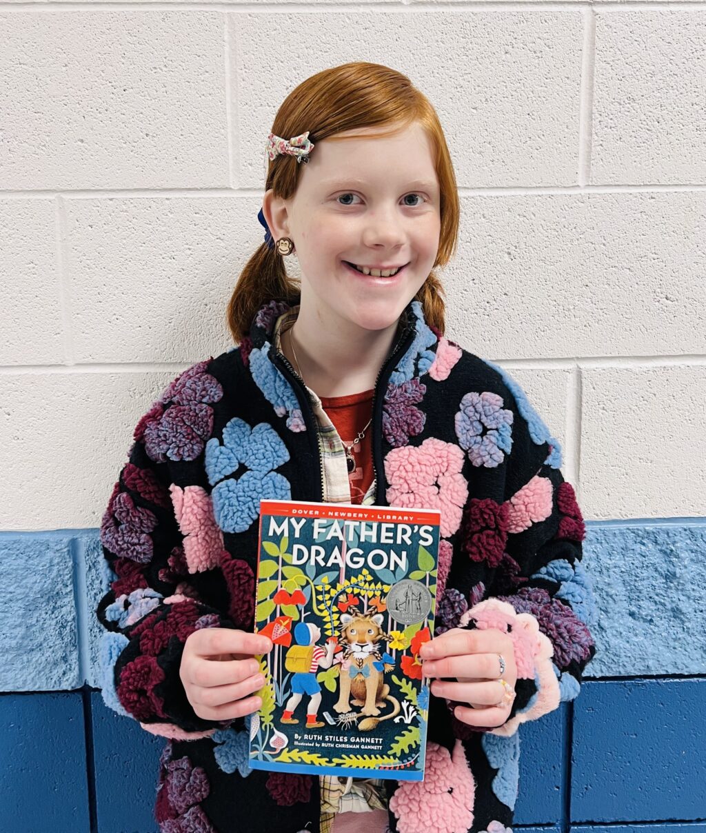 student holding a book they earned through a special recognition