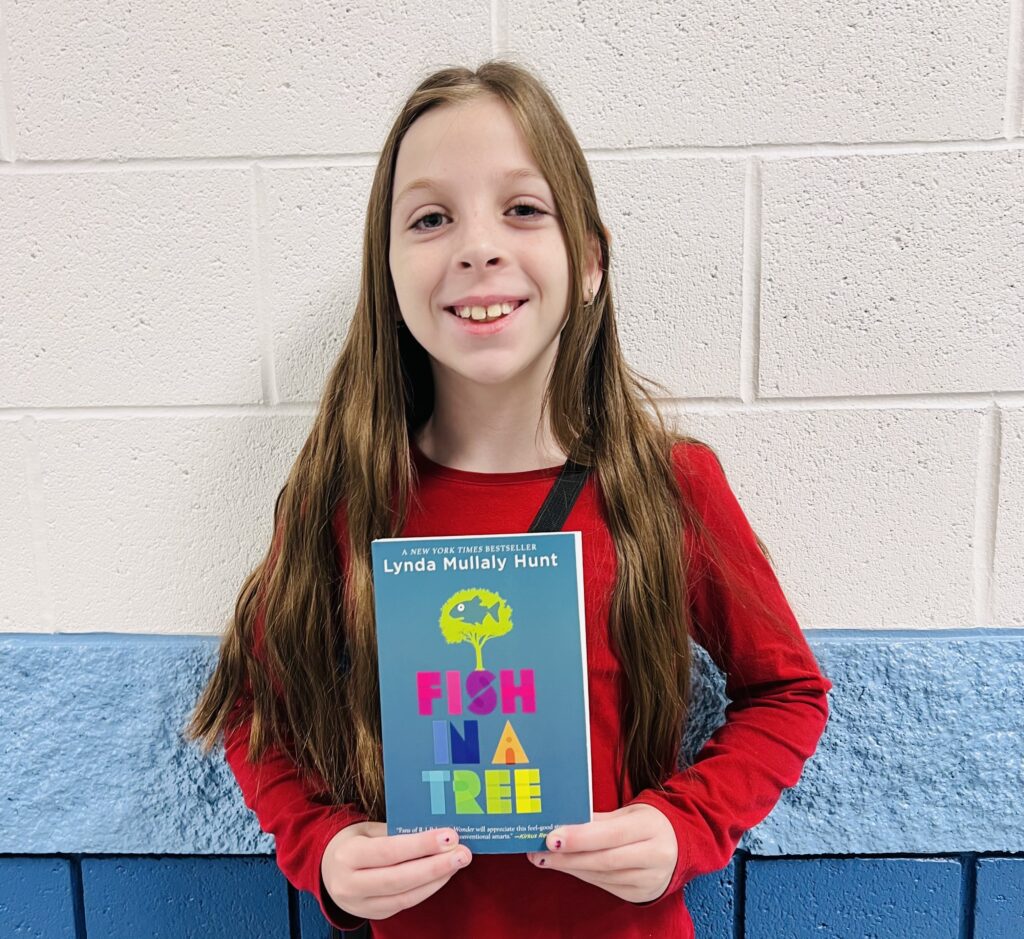 student holding a book they earned through a special recognition