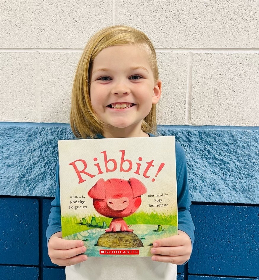 student holding a book they earned through a special recognition