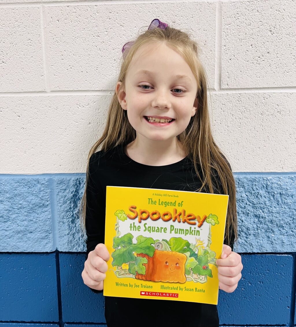 student holding a book they earned through a special recognition