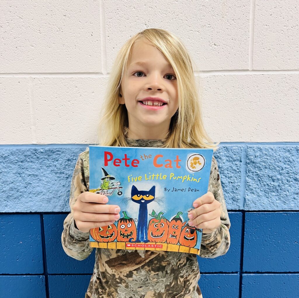 student holding a book they earned through a special recognition