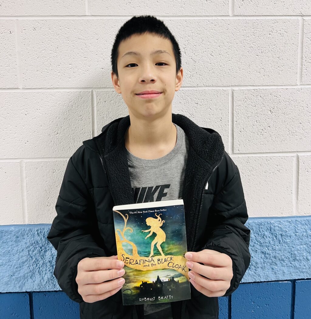 student holding a book they earned through a special recognition