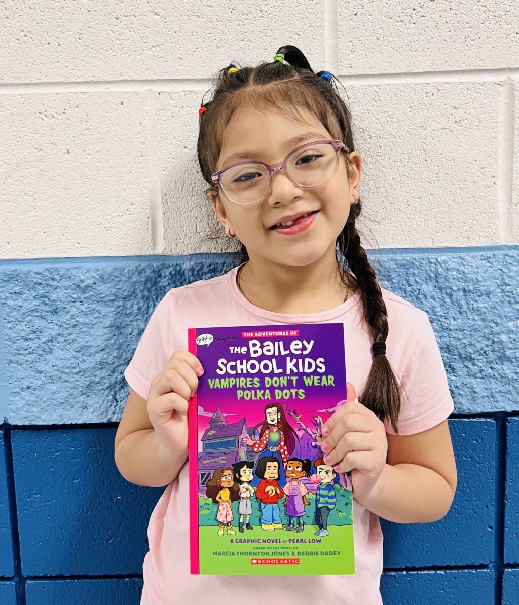 student holding a book they earned through a special recognition