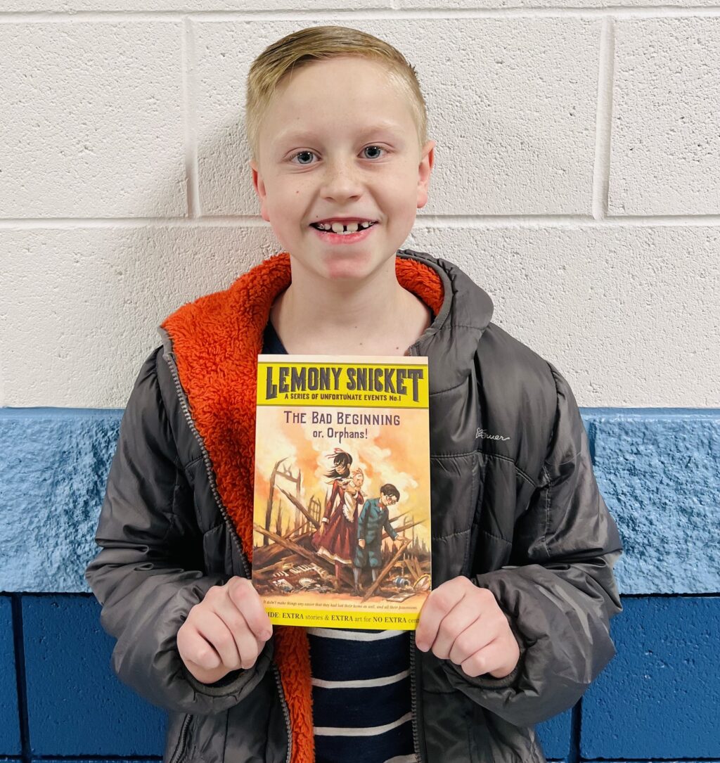 student holding a book they earned through a special recognition