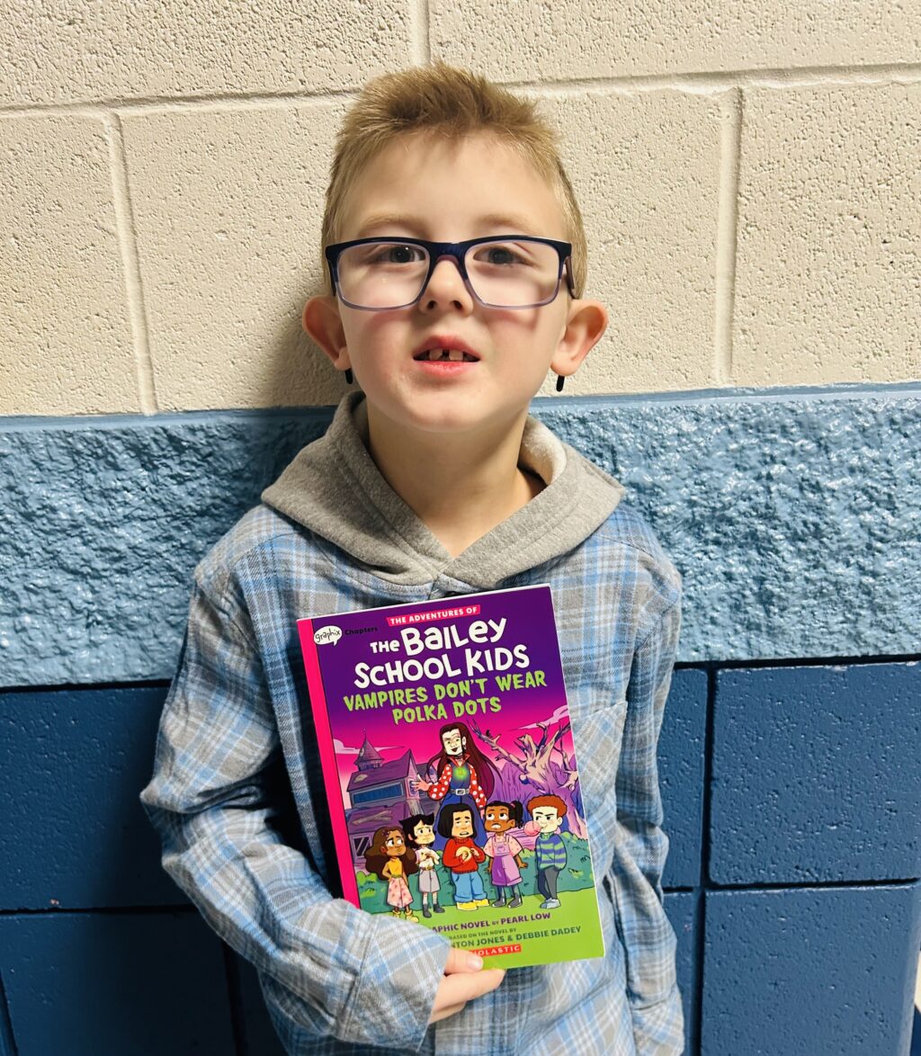 student holding a book they earned through a special recognition