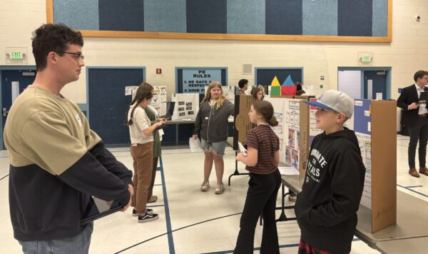 Amelia Earhart students are talking with STEM fair judges about their projects.