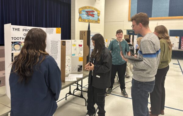 Amelia Earhart students are talking with STEM fair judges about their projects.