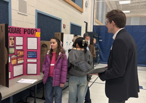 Amelia Earhart students are talking with STEM fair judges about their projects.