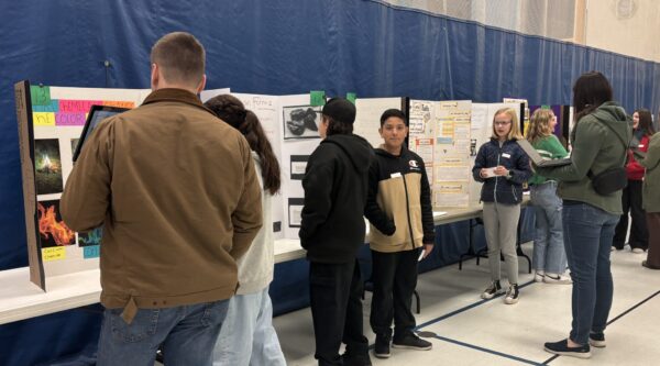 Amelia Earhart students are talking with STEM fair judges about their projects.