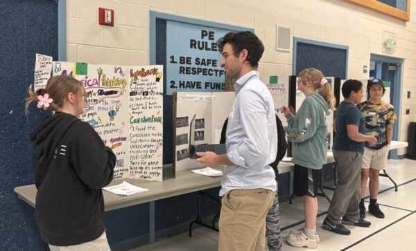 Amelia Earhart students are talking with STEM fair judges about their projects.