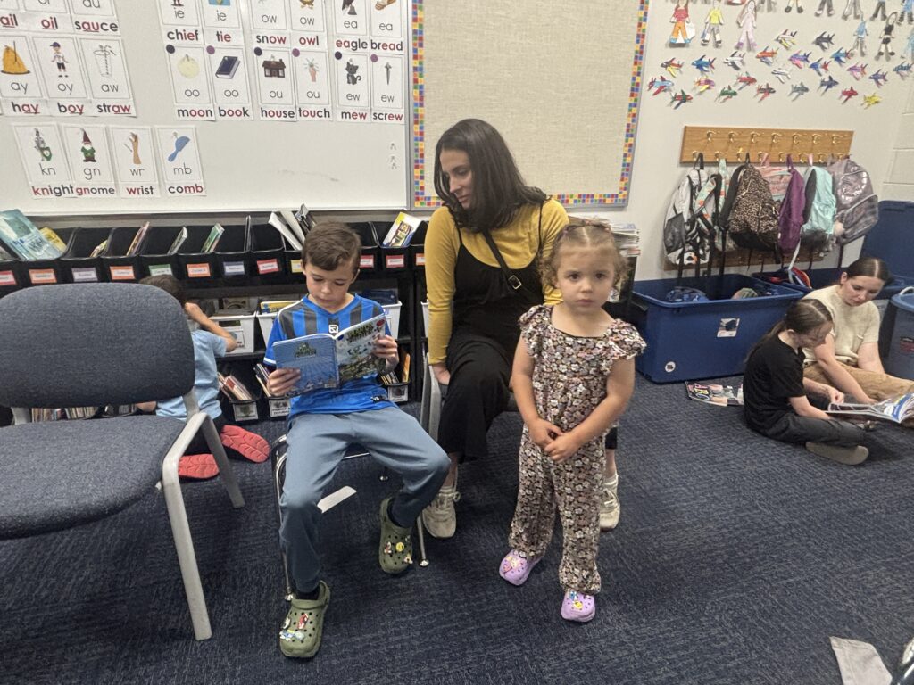 Students reading with  guests that could be parents, grandparents, family friends, or faculty and staff for read with a child day in May