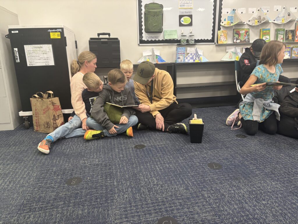 Students reading with  guests that could be parents, grandparents, family friends, or faculty and staff for read with a child day in May
