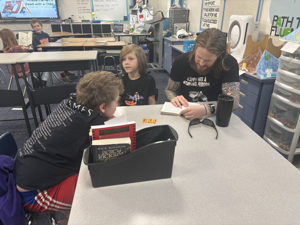 Students reading with  guests that could be parents, grandparents, family friends, or faculty and staff for read with a child day in May