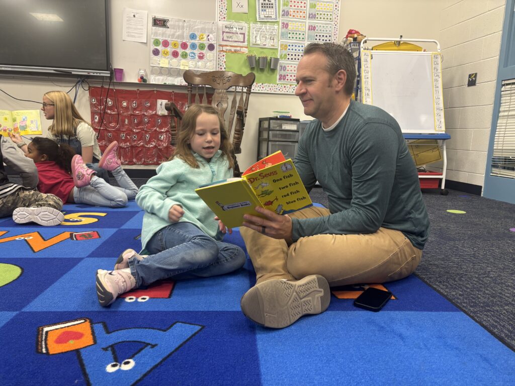 Students reading with  guests that could be parents, grandparents, family friends, or faculty and staff for read with a child day in May