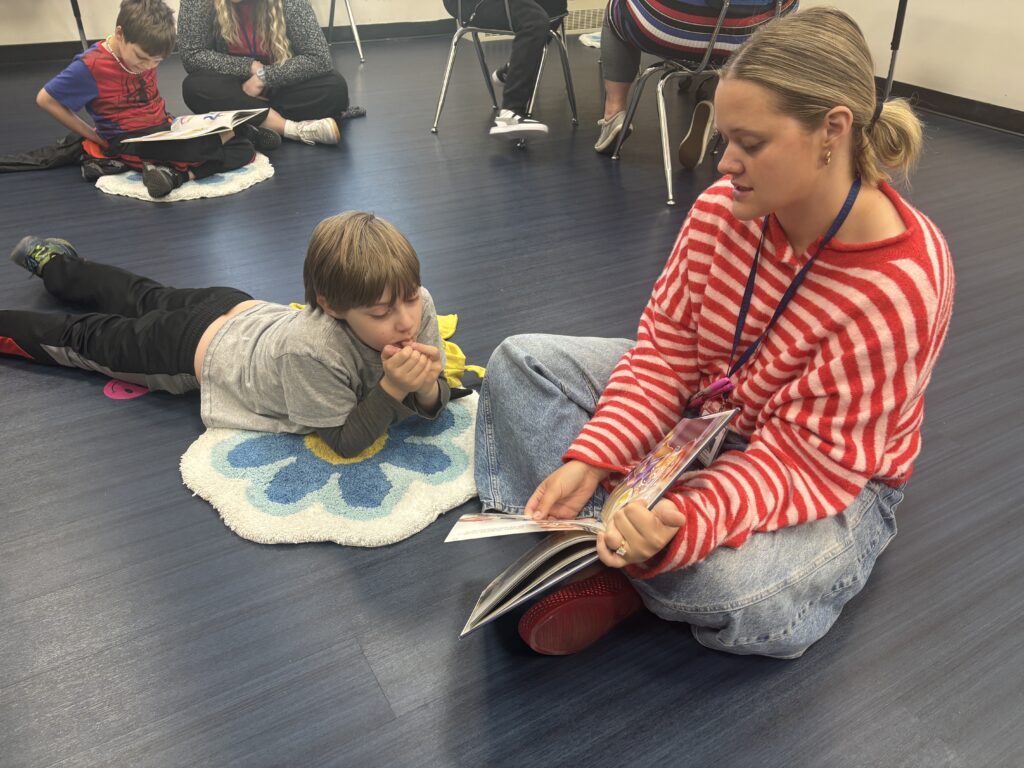 Students reading with  guests that could be parents, grandparents, family friends, or faculty and staff for read with a child day in May