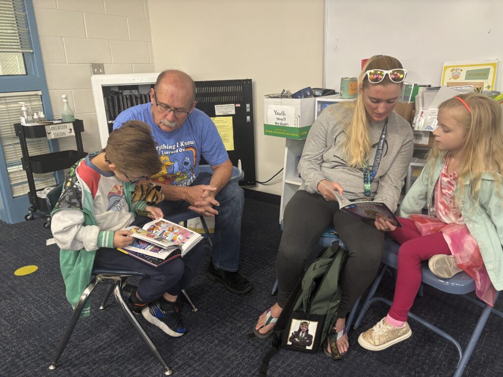 Students reading with  guests that could be parents, grandparents, family friends, or faculty and staff for read with a child day in May