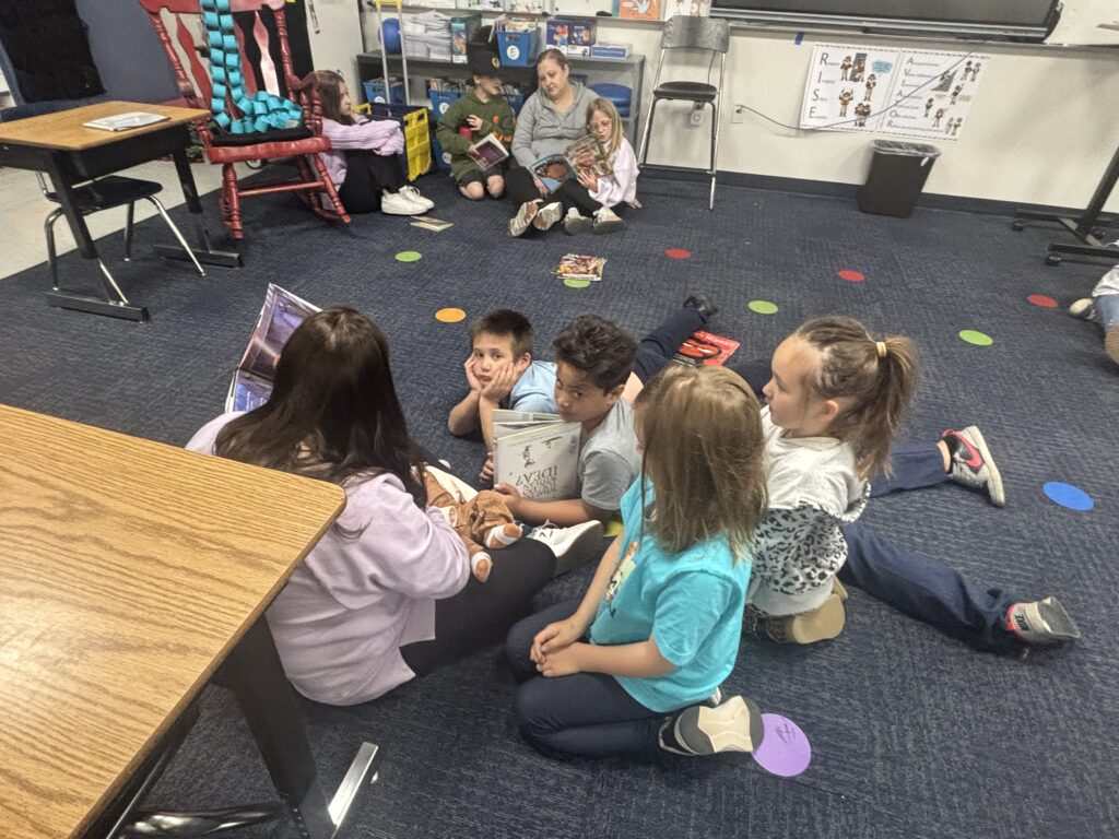 Students reading with  guests that could be parents, grandparents, family friends, or faculty and staff for read with a child day in May