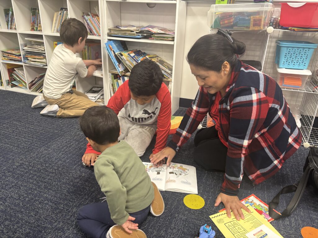 Students reading with  guests that could be parents, grandparents, family friends, or faculty and staff for read with a child day in May